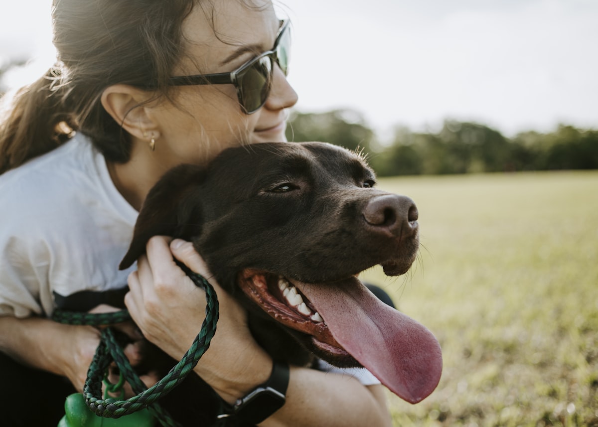 Una persona abrazando a su perro al aire libre